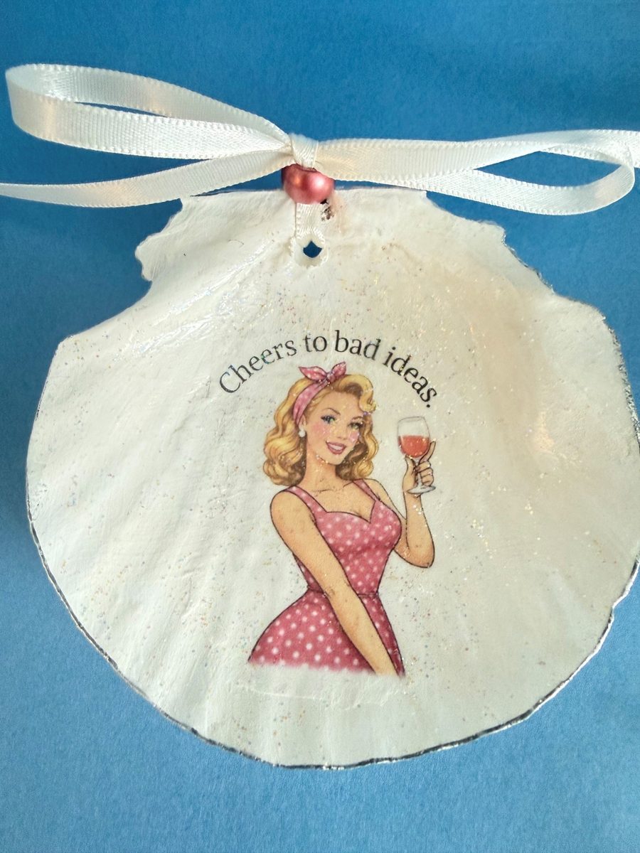 Scallop shell with a retro woman raising a glass of wine and the words Cheers to bad ideas